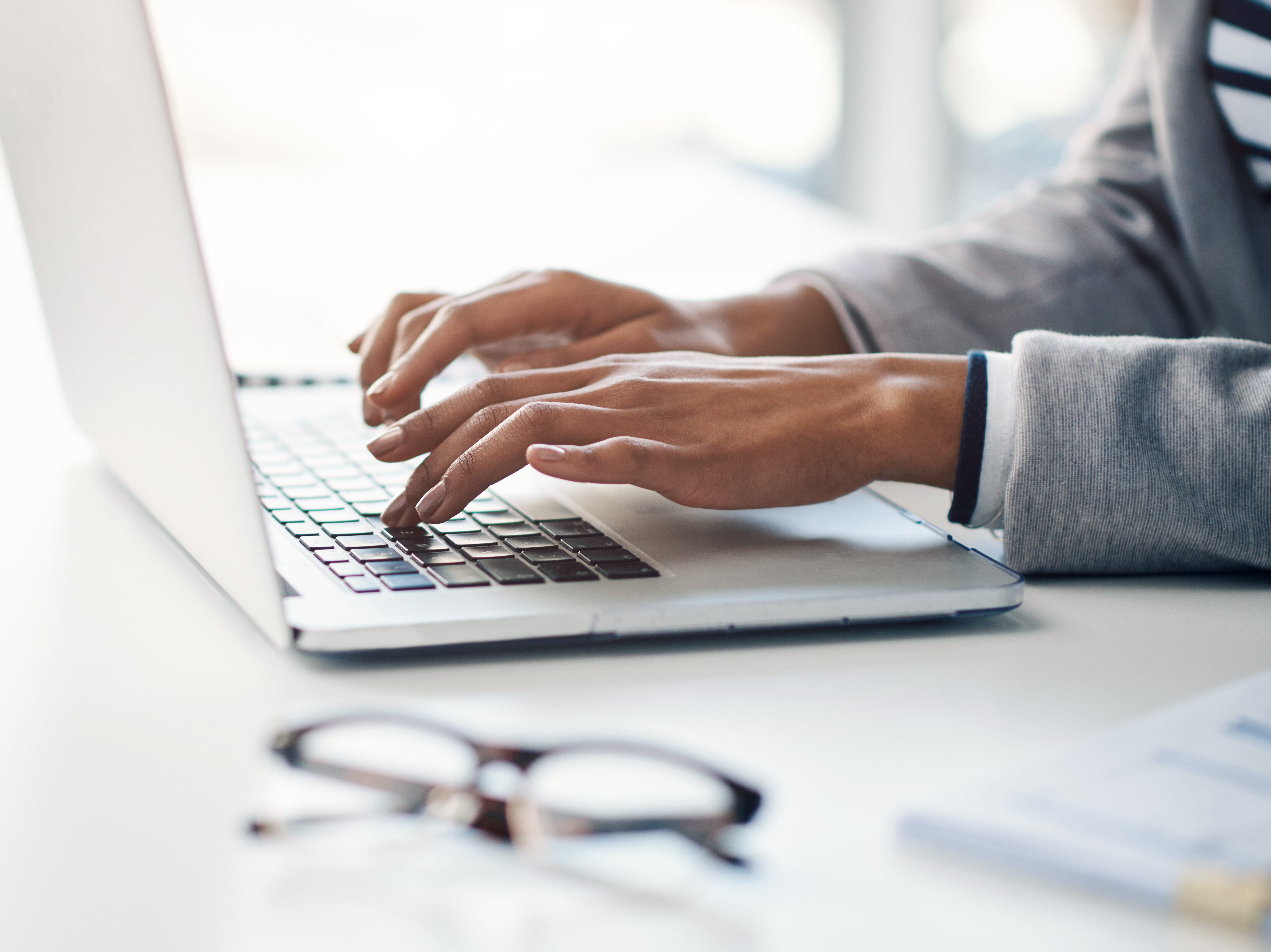 Office, typing and hands of woman at laptop for research, business review or online report at agency. Budget, planning and consultant at desk with computer, networking and financial risk management